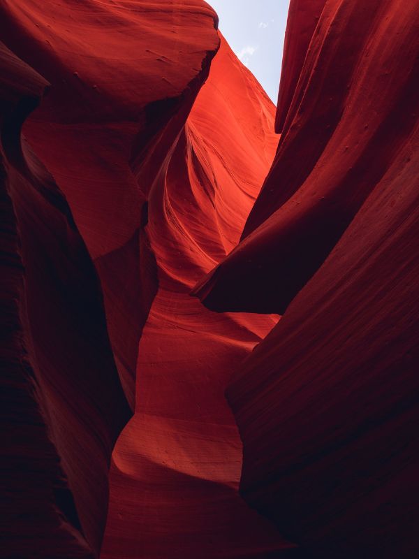 Red canyon walls that open to a faint blue sky